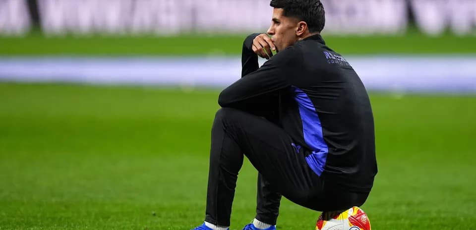 Jugador sentado en el campo con balón a sus pies
