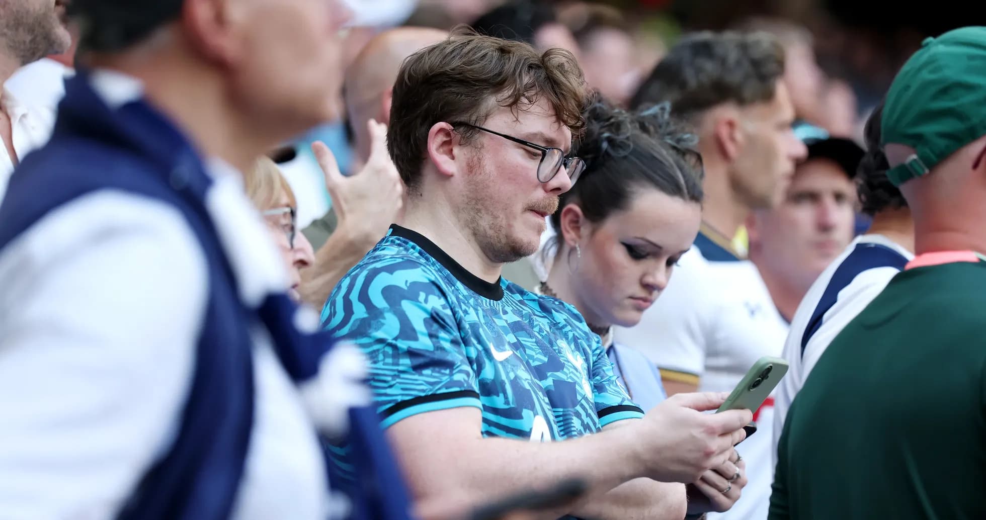 Espectadores en un evento deportivo revisando sus teléfonos