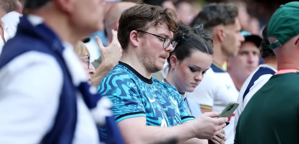 Espectadores en un evento deportivo revisando sus teléfonos