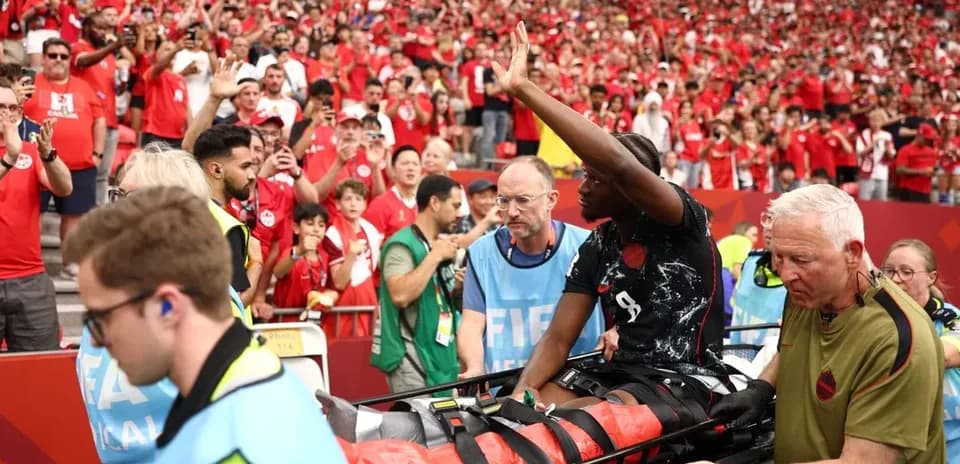 Jugador en camilla mientras aficionados animan en el estadio