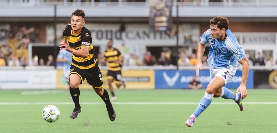 Jugador corriendo con balón en partido de fútbol