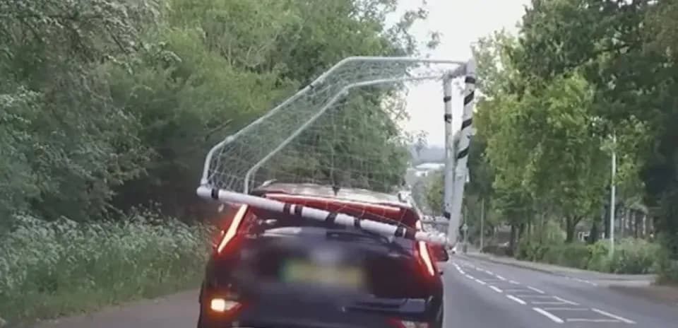 Coche transportando una portería de fútbol en la carretera