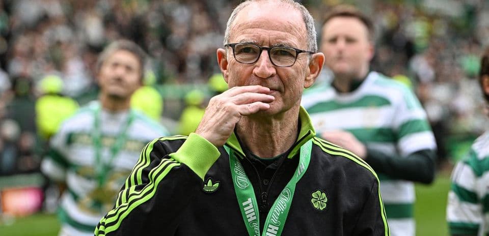 Entrenador en el campo con medalla y aficionados al fondo
