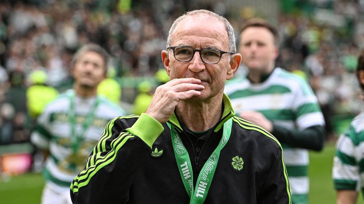 Entrenador en el campo con medalla y aficionados al fondo