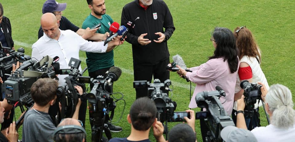 Entrenador dando una conferencia de prensa rodeado de periodistas
