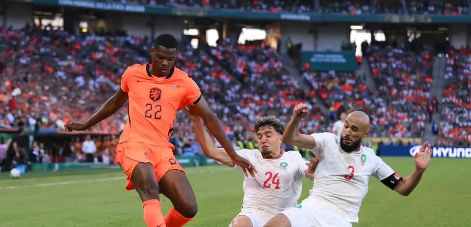 Jugador de Países Bajos driblando entre defensores marroquíes