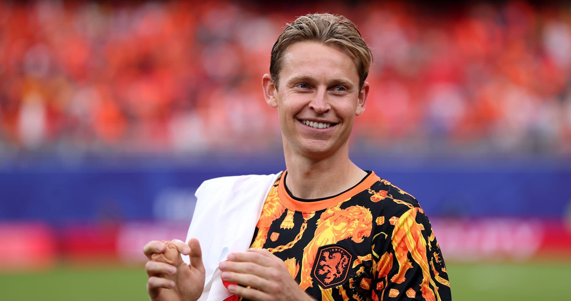 Jugador sonriendo con camiseta naranja en el campo