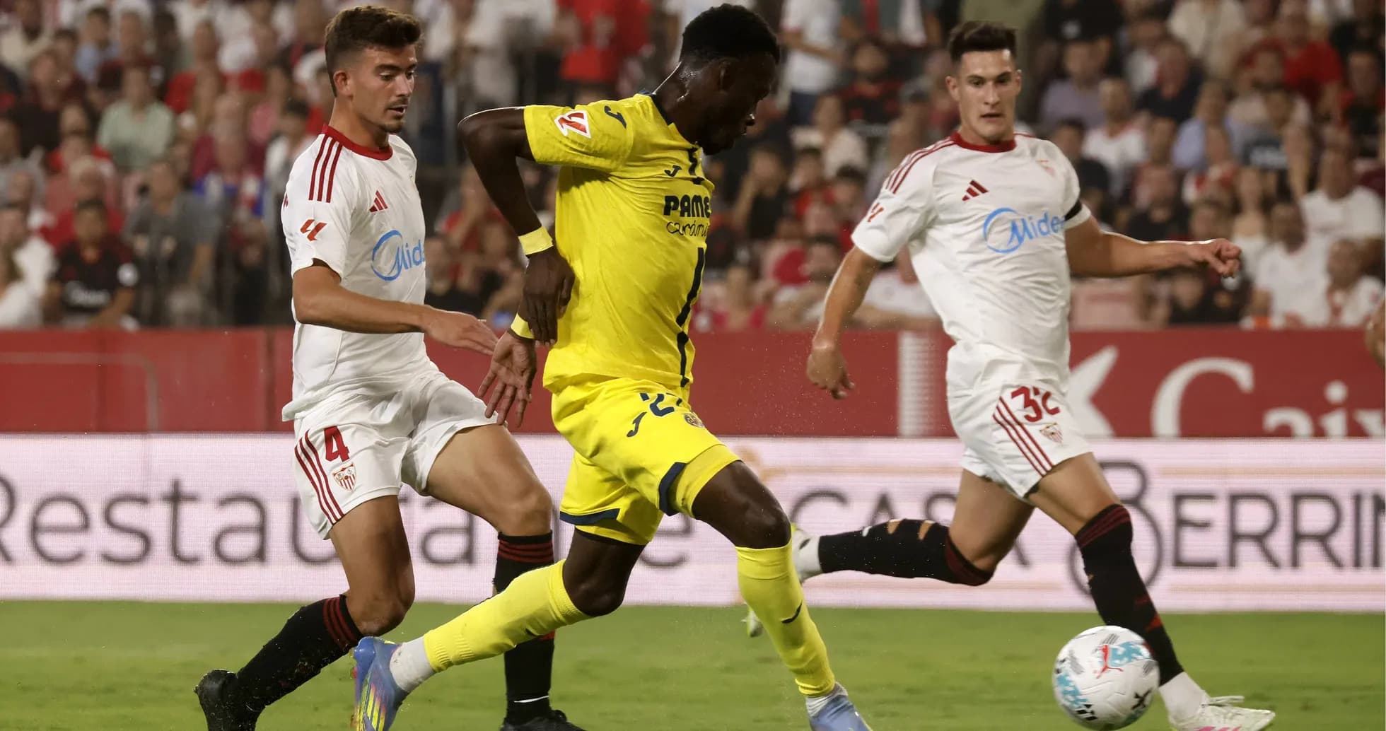 Jugador de Villarreal esquivando a defensores de Sevilla