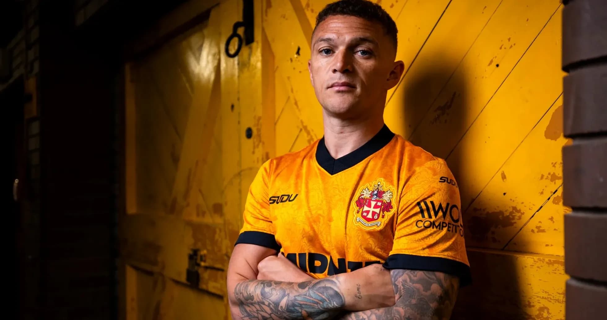 Jugador posando con camiseta de equipo en fondo amarillo