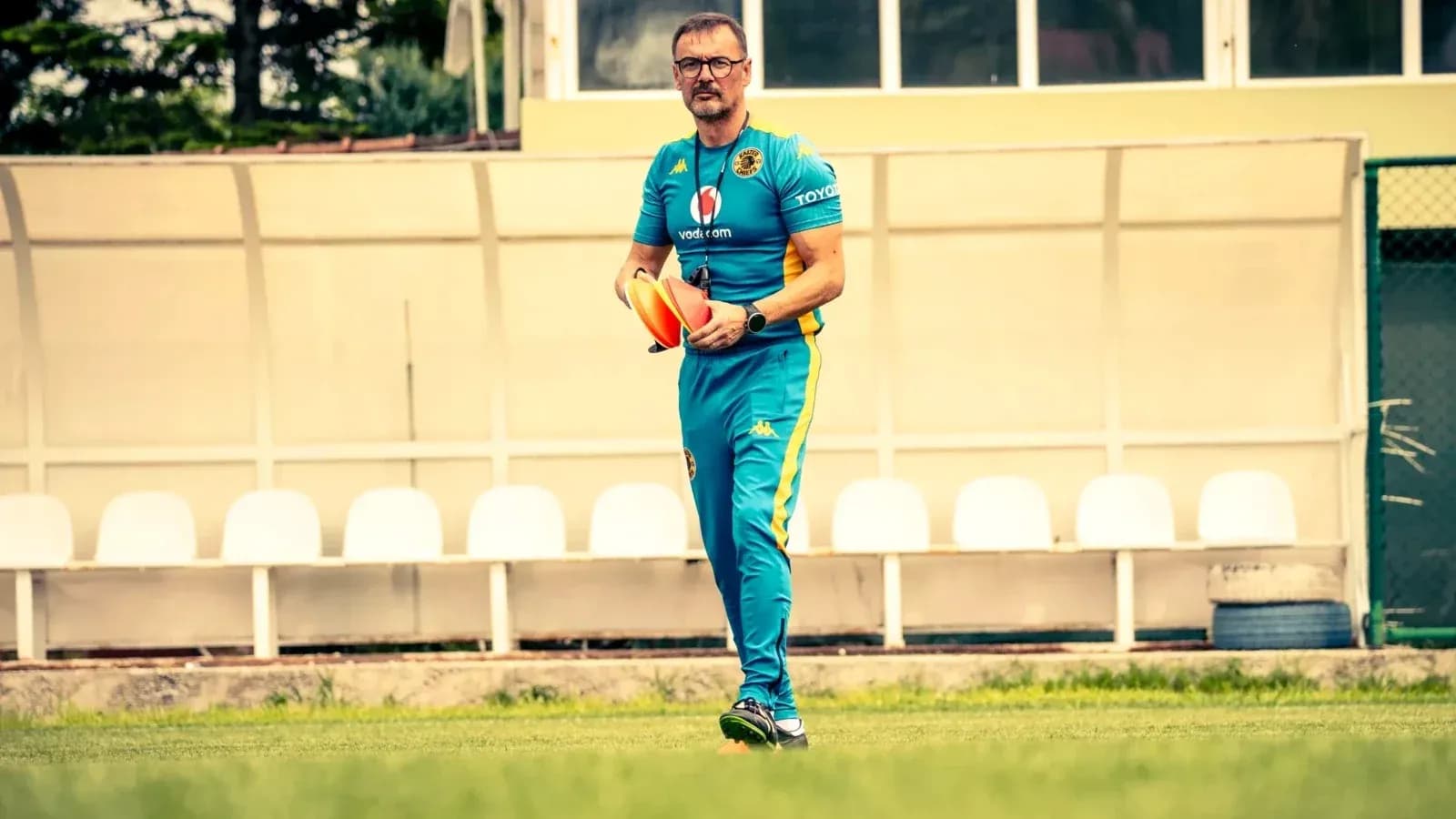 Entrenador sosteniendo conos en el campo de entrenamiento