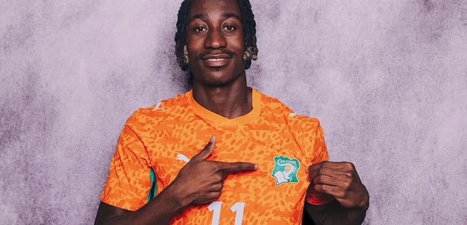 Jugador con camiseta naranja de Côte d'Ivoire señalando escudo