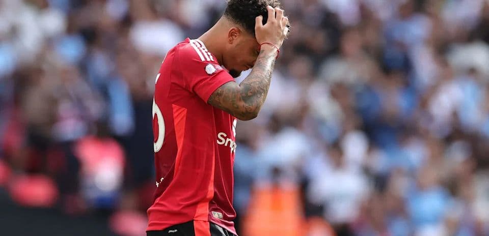 Jugador con camiseta roja mirando hacia abajo en el campo
