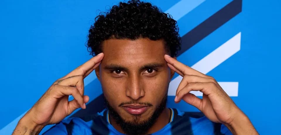 Jugador posando con fondo azul en camiseta deportiva