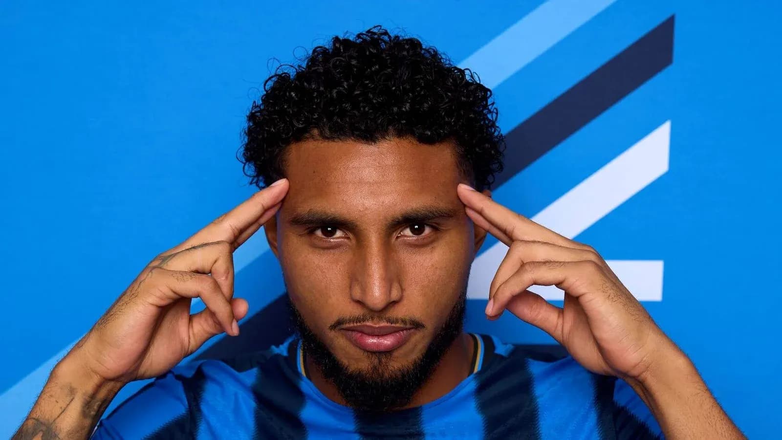 Jugador posando con fondo azul en camiseta deportiva