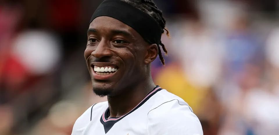 Jugador sonriente con camiseta blanca en el campo