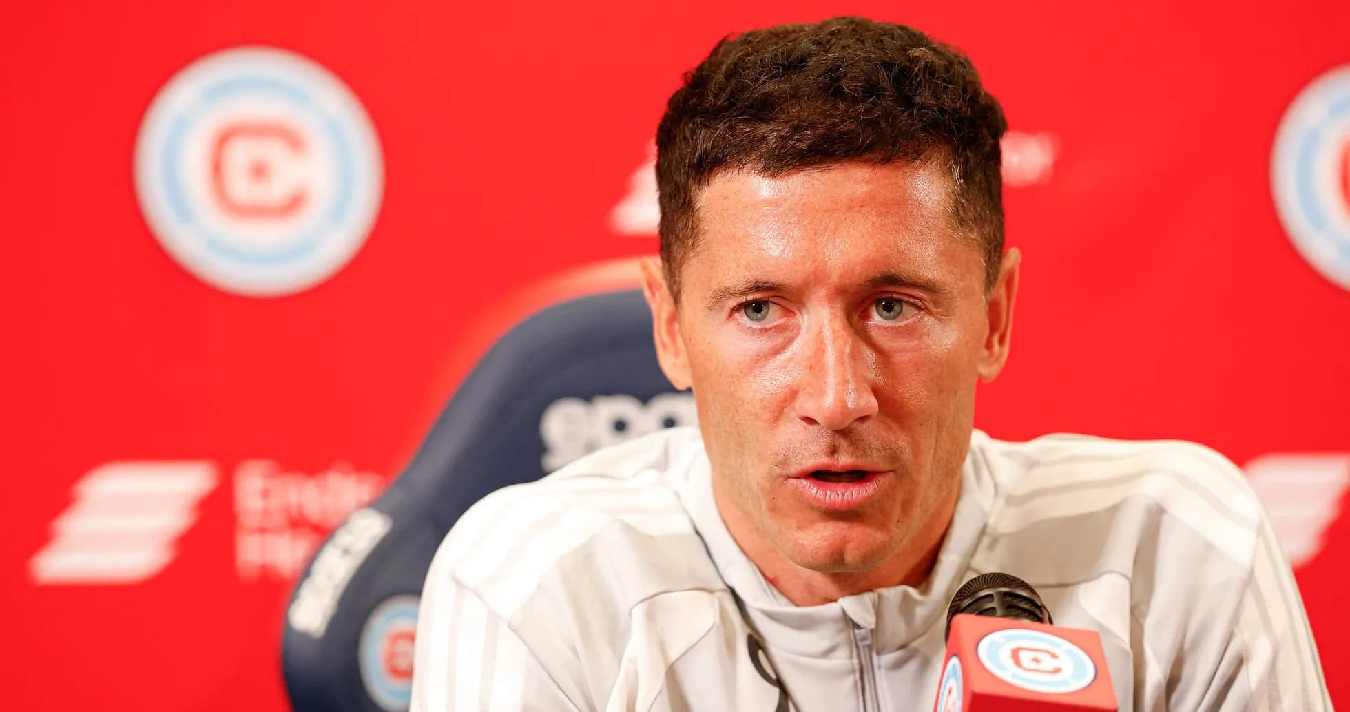 Jugador en conferencia de prensa con fondo rojo