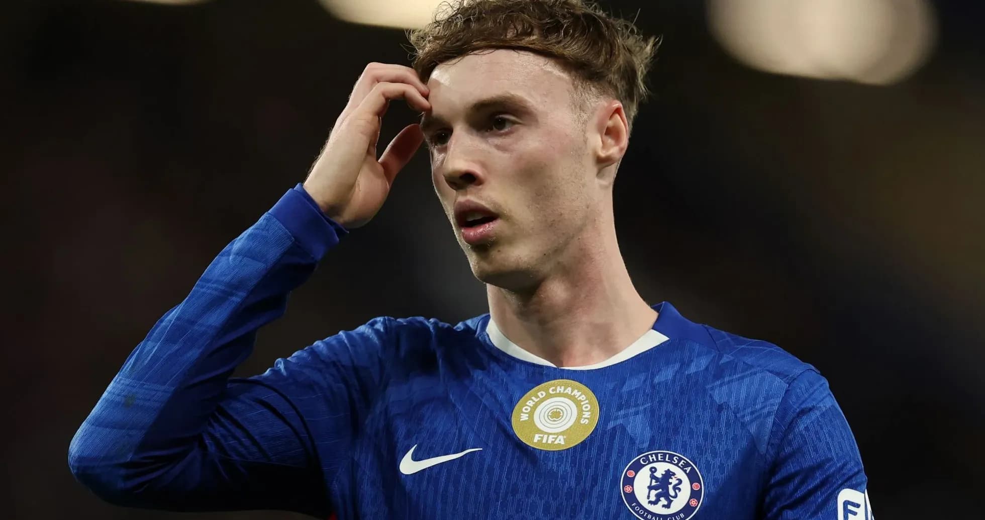 Jugador de Chelsea con camiseta azul, pensativo en el campo