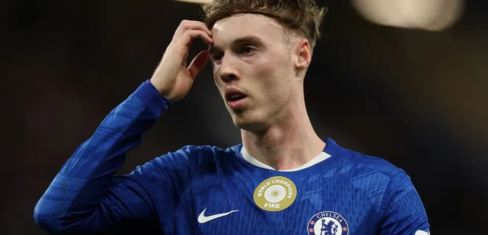 Jugador de Chelsea con camiseta azul, pensativo en el campo