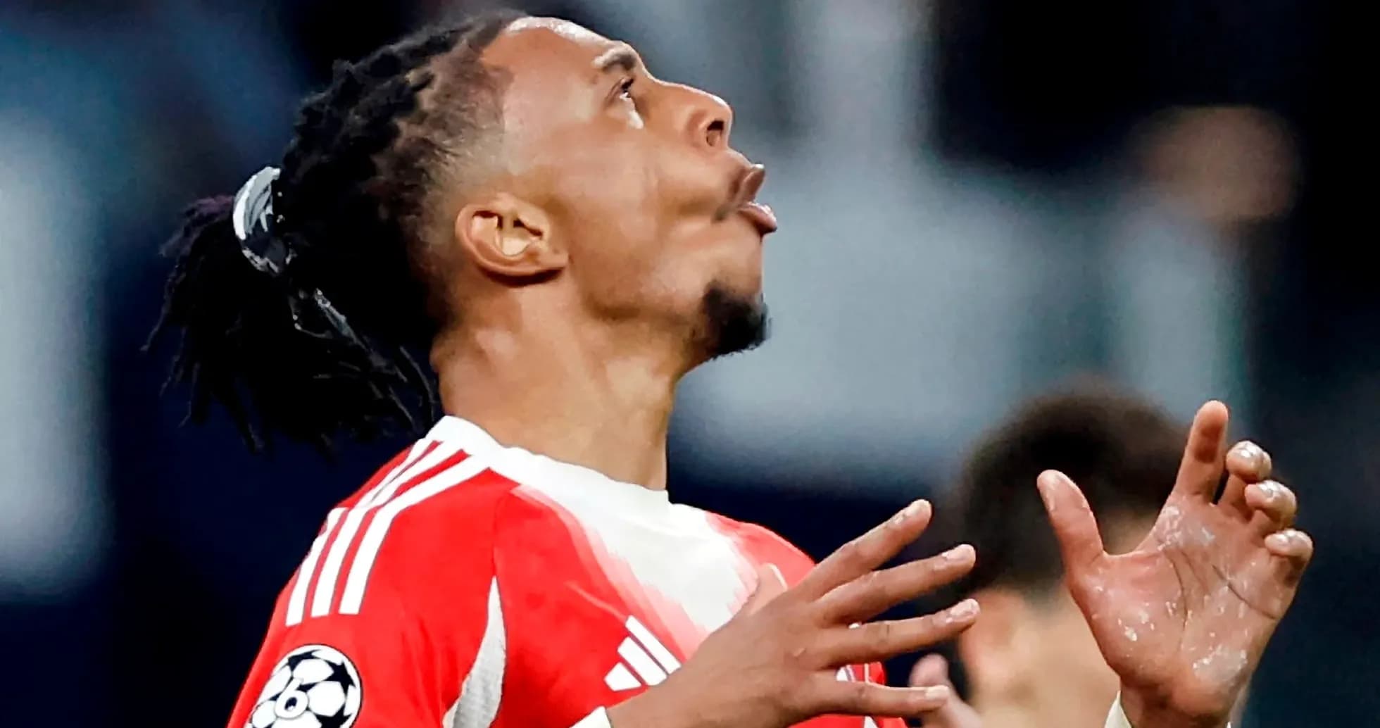 Jugador de fútbol con camiseta roja mirando al cielo