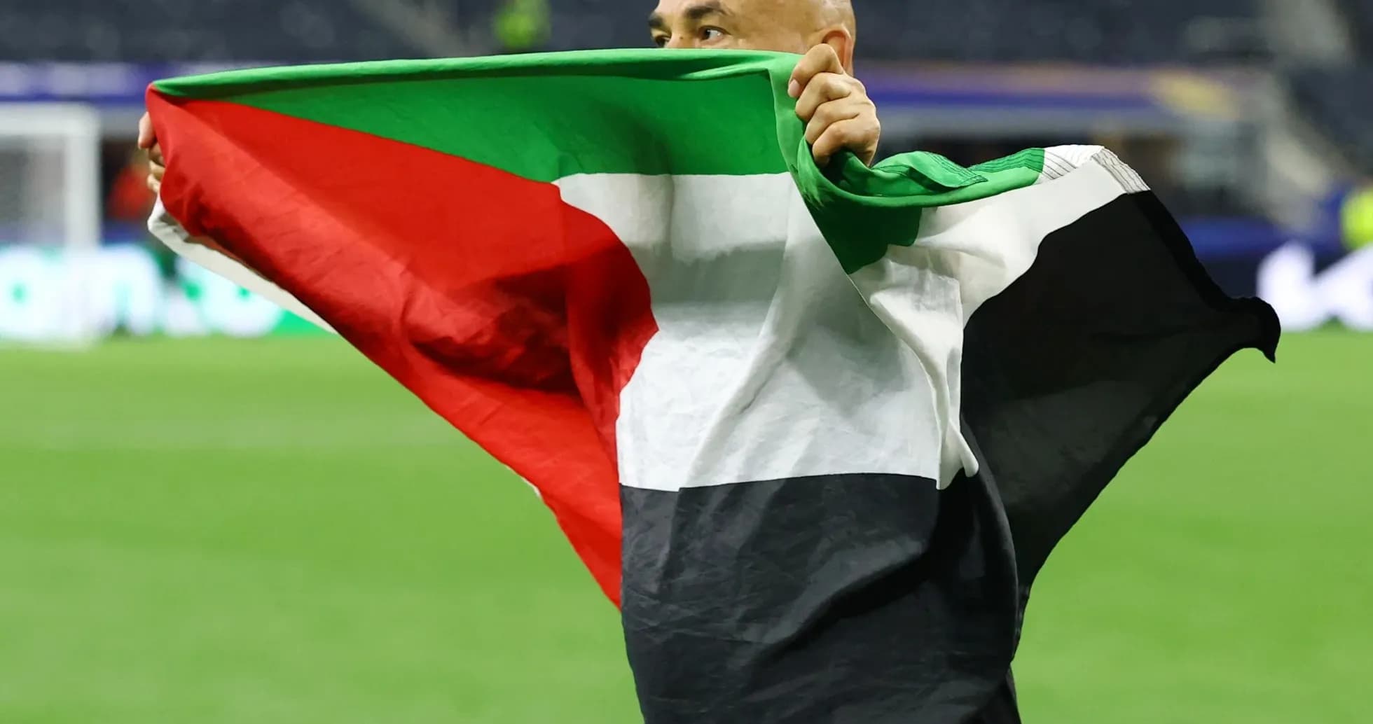 Persona sosteniendo una bandera en el campo de juego Persona sosteniendo una bandera en el campo de juego